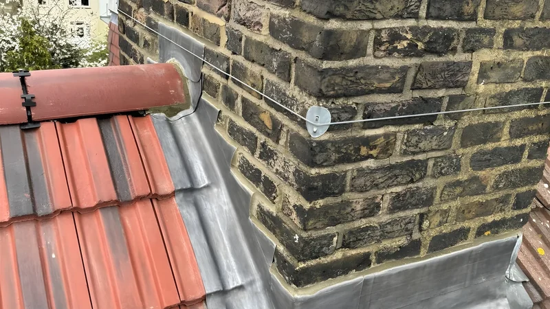 Completed leadwork repair at a chimney and roof junction