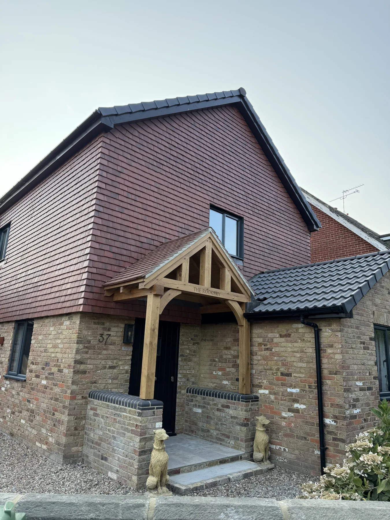 Completed bespoke oak porch, brick walls and tiled roof junction in West End, Surrey